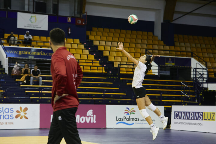 Jugadora sacando con entrenador mirando